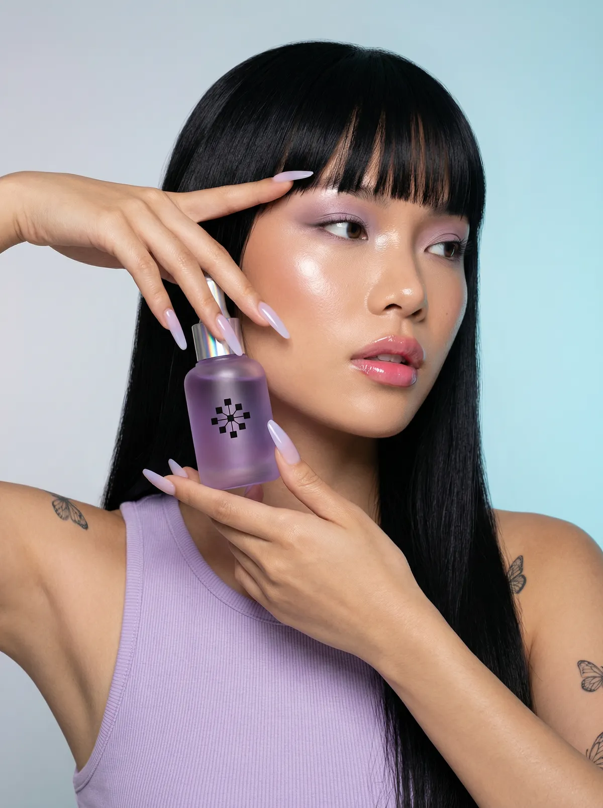 Model with a straight fringe holding a lilac perfume bottle