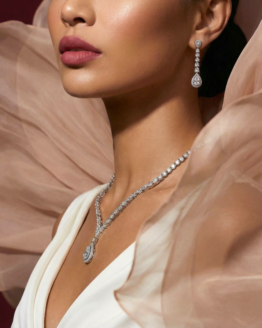 Close-up of a diamond necklace and drop earrings against blush tulle